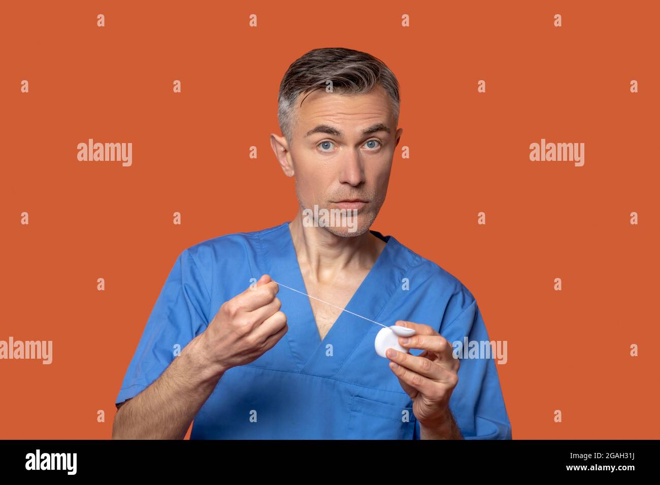 Hombre con ropa médica con hilo dental en las manos Fotografía de stock -  Alamy