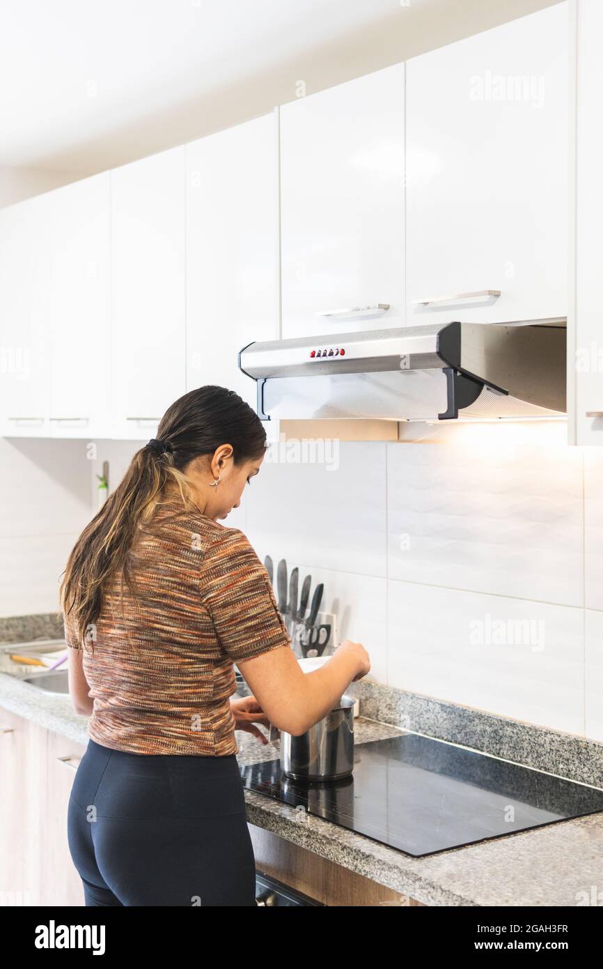 Asistencia piel cola Mujer cocinando en la cocina sobre una placa de inducción con un extractor  de olores Fotografía de stock - Alamy