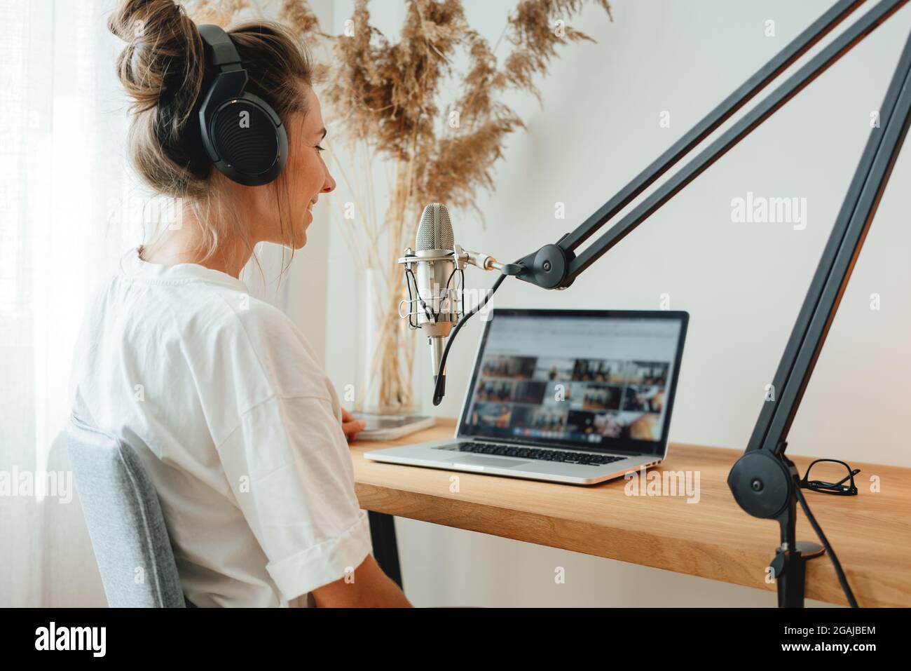 Mujer podcaster grabando su podcast utilizando el micrófono y el portátil  en su pequeño estudio de emisión en casa. Mujer transmitiendo en directo  desde un estudio de radio casero Fotografía de stock -