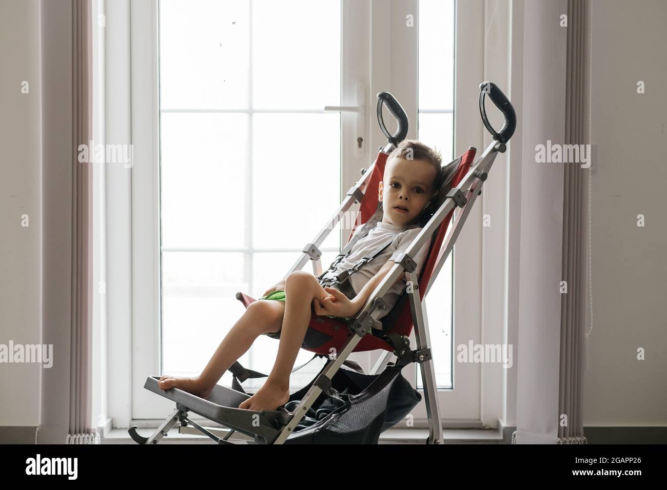 Chico con Parálisis Cerebral en silla especial saliendo por la puerta.  Accesibilidad para personas con discapacidad en prados Fotografía de stock  - Alamy