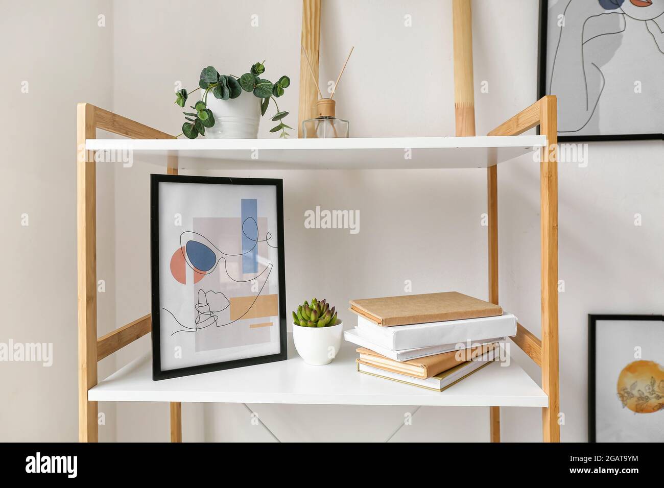 Estantería con libros y decoración cerca de la pared blanca habitación  Fotografía de stock - Alamy