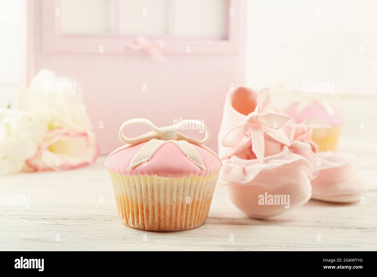 Sabrosa cupcake con arco y zapatos para bebé, carro decorativo para bebés  sobre fondo de color Fotografía de stock - Alamy
