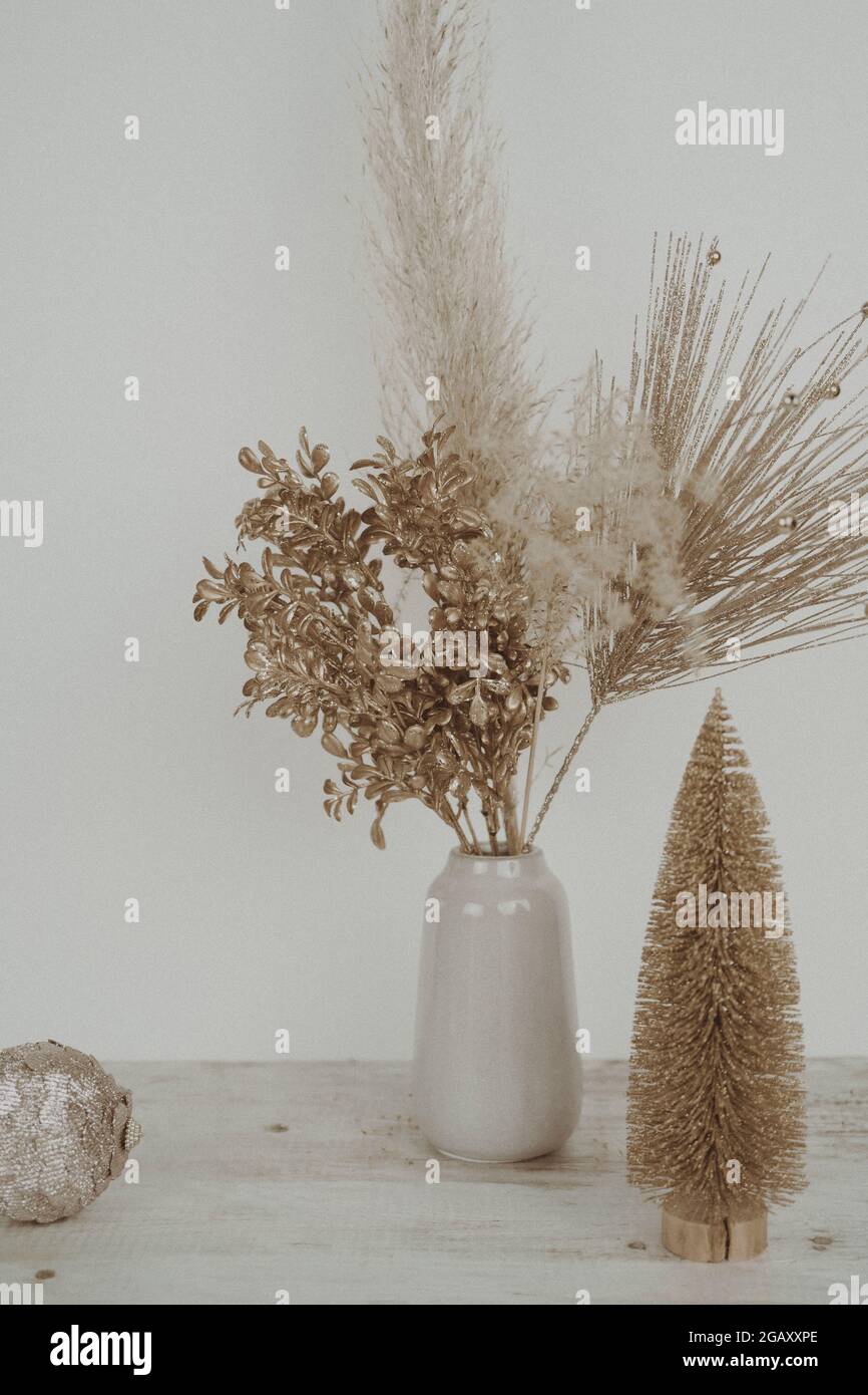 Jarrón con pampas secas sobre fondo neutro con árbol de Navidad y bola  cerca de la pared. Seco pampas de hierba, caña en jarrón con estilo.  Fotografías de alta calidad Fotografía de