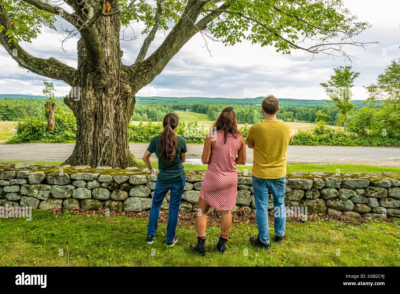 Tres personas mirando hacia una hermosa vista desde una granja en la cima de una colina en el centro norte de Massachusetts Foto de stock