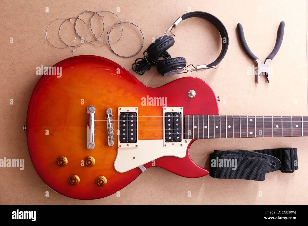 Guitarra eléctrica con auriculares, alicates y cuerdas sobre fondo beige  Fotografía de stock - Alamy