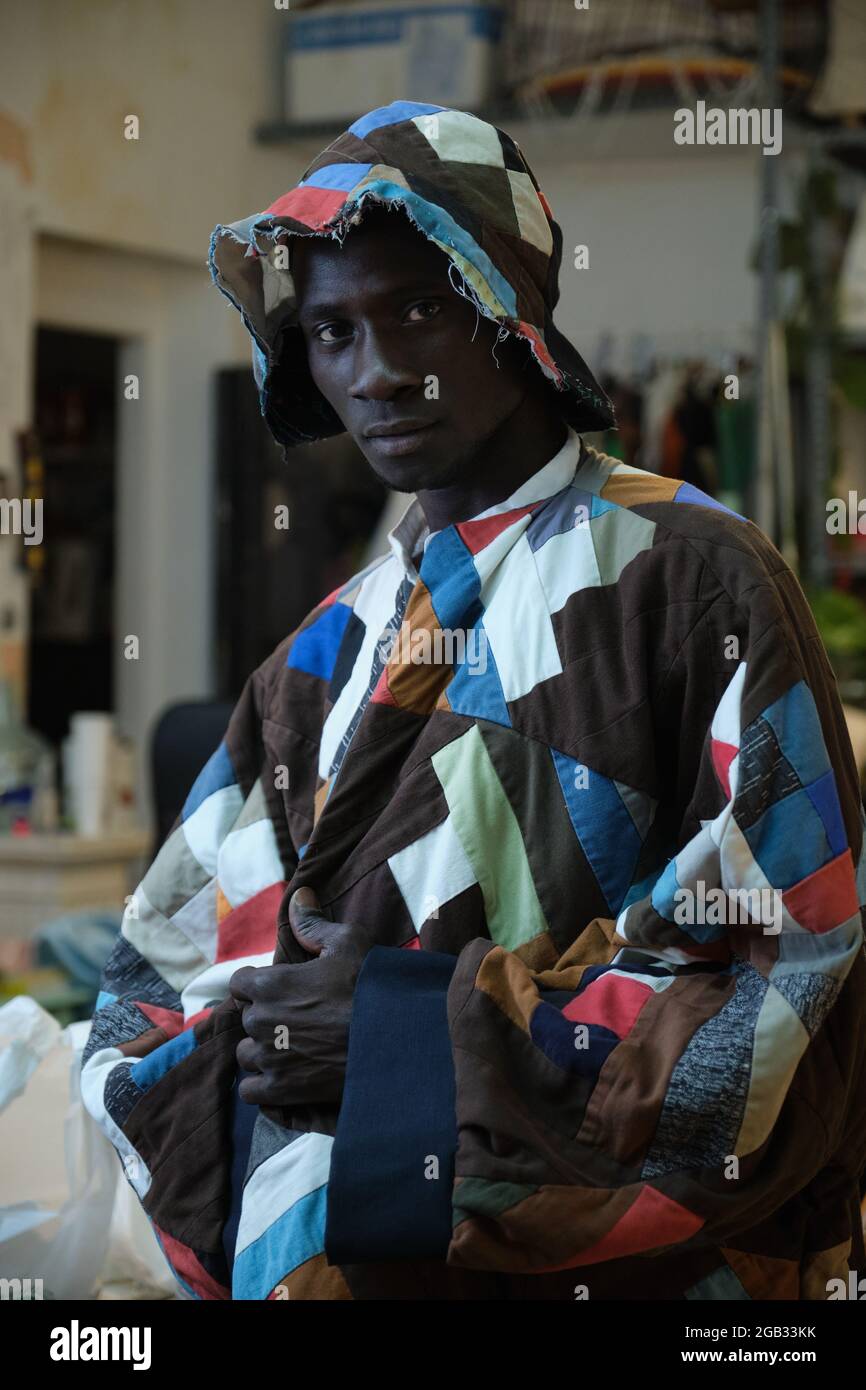 Un hombre africano que llevaba ropa y sombrero tradicionales de colores en  su taller de costura Fotografía de stock - Alamy