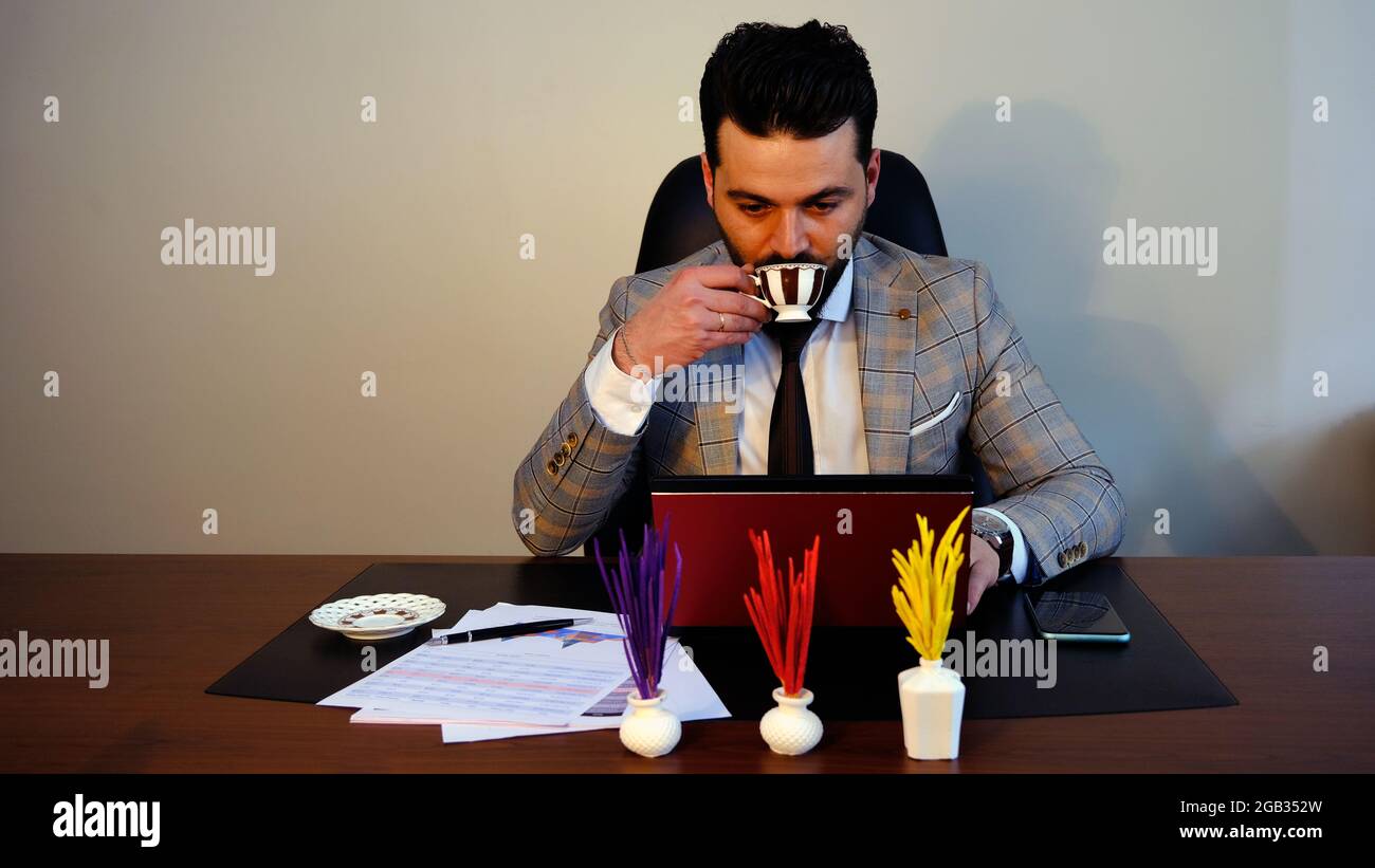 hombre de negocios bebiendo café y trabajando con computadora en el escritorio de la oficina. Foto de stock