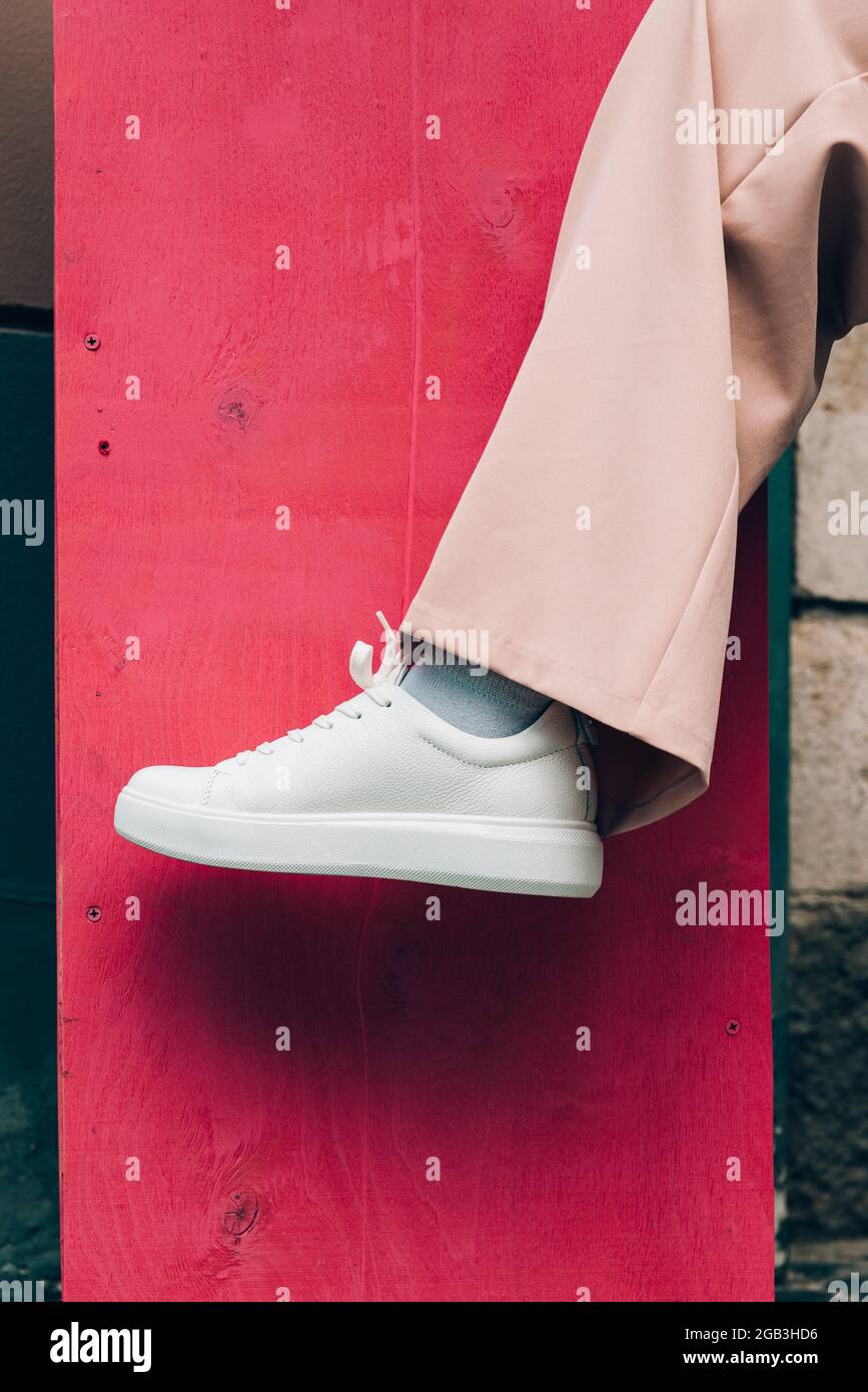 Mujer con estilo con zapatos de sneakers blancos de moda y pantalones  beige. Fondo rosa Fotografía de stock - Alamy