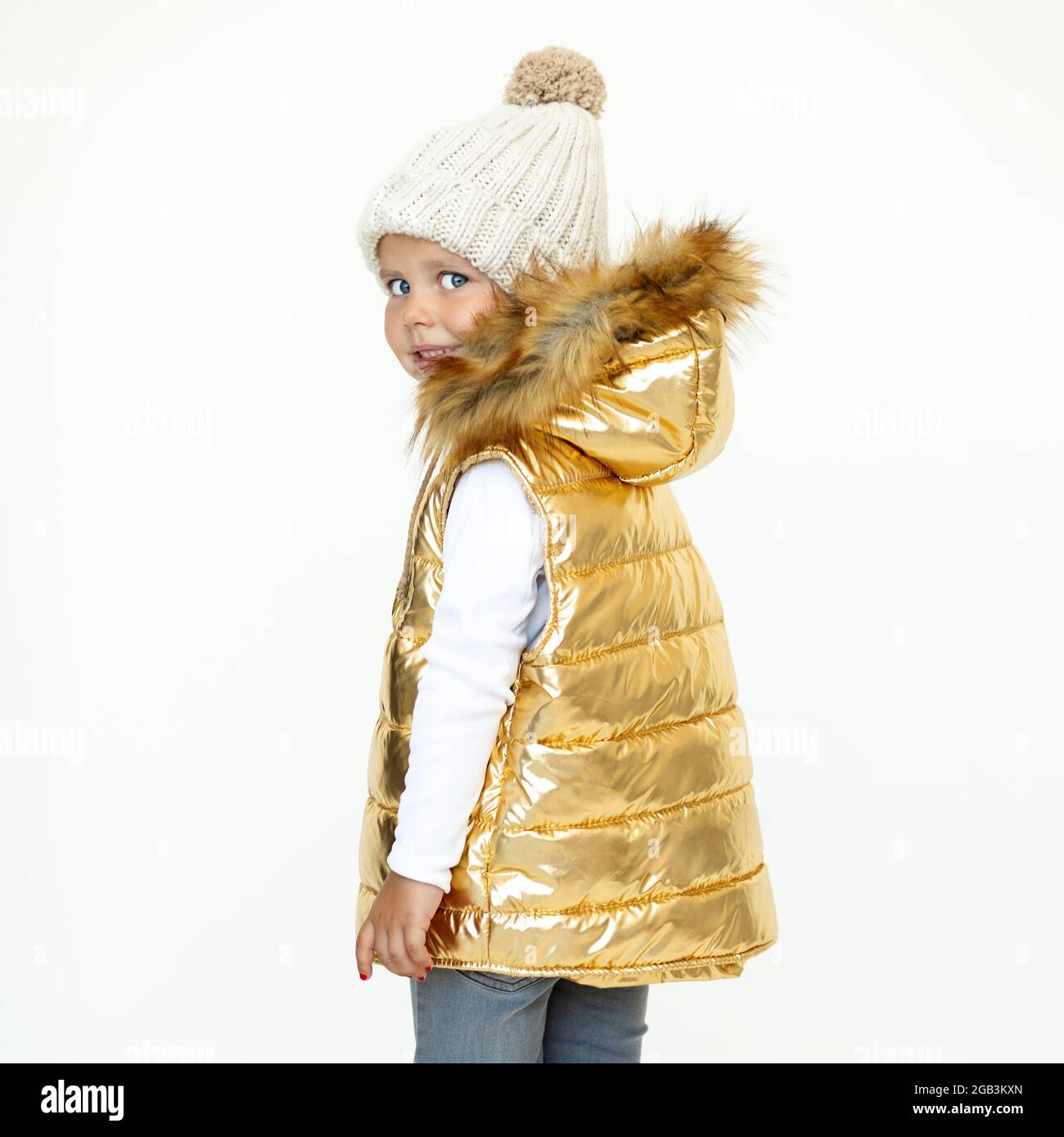 niña pequeña hermosa en chaleco acolchado de color oro capucha, cálido sombrero de lana de oveja. Foto de estudio sobre fondo blanco Fotografía de stock - Alamy