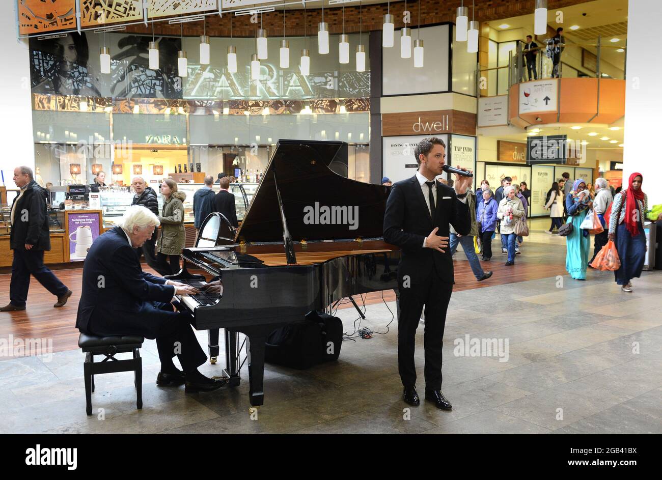 El vocalista Jordan Williams y el pianista de jazz Brian Dee entretiene a los compradores en Touchwood Shopping Center, Solihull, Gran Bretaña, Reino Unido Foto de stock