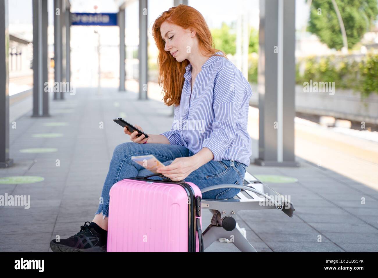 Mujer esperando el tren viendo el teléfono inteligente Foto de stock