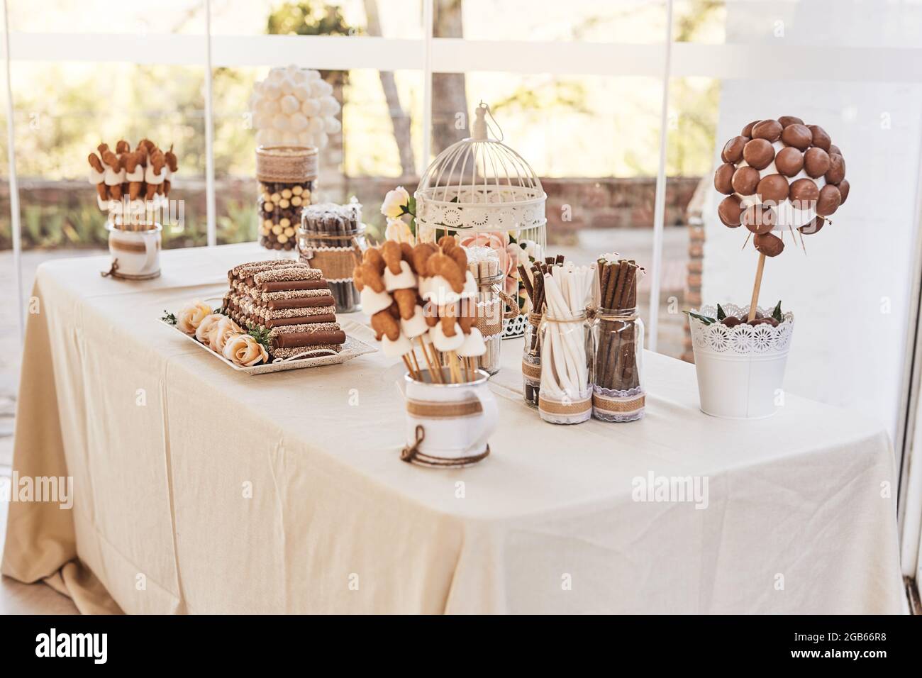 Mesa de chocolate blanco y negro dulce con chocolates hechos a mano, toques  de pastel, rosas y decoraciones en una elegante recepción de bodas. Toma  con li natural Fotografía de stock -