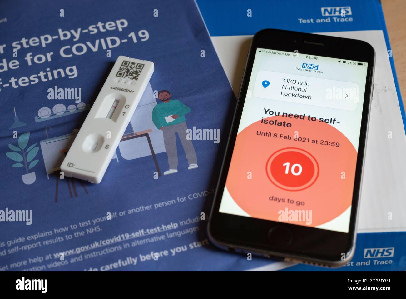 Un iPhone que muestra un mensaje de aislamiento durante la pandemia de Covid-19 en 2021, con una prueba de Covid negativa y un folleto. Foto de stock