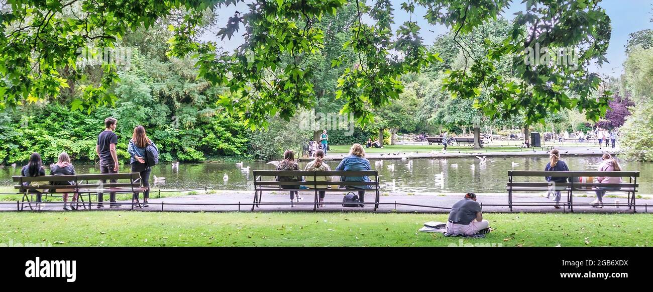 Gente disfrutando de una tarde soleada, junto al estanque de patos en St Stephens Green en Dublín, Irlanda. Foto de stock