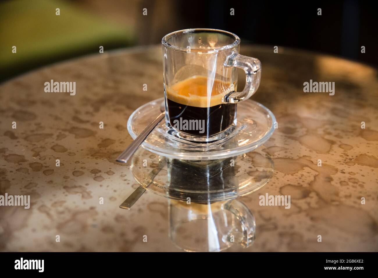 Primer plano retrato de una elegante taza de café expreso sentado en una mesa con espejo de colores con reflejos. Foto de stock