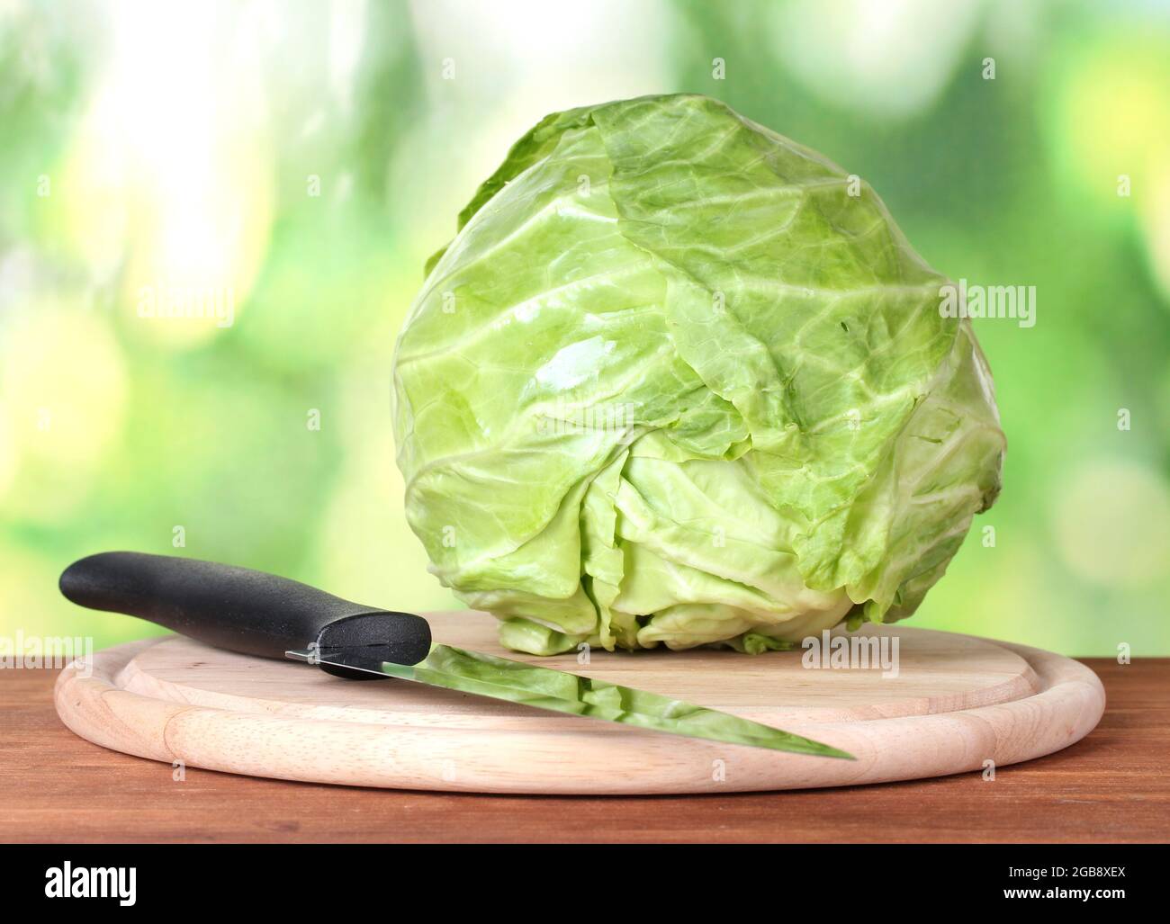 El repollo en una tabla para cortar con un cuchillo sobre fondo verde  colorido Fotografía de stock - Alamy