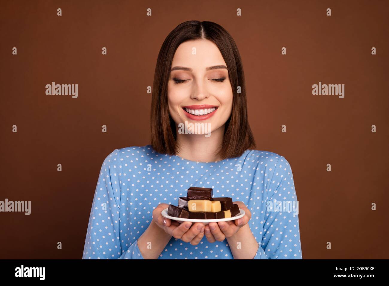 Foto de alegre pelo corto joven dama sostener chocolate ropa blusa azul  aislado sobre fondo de color marrón Fotografía de stock - Alamy