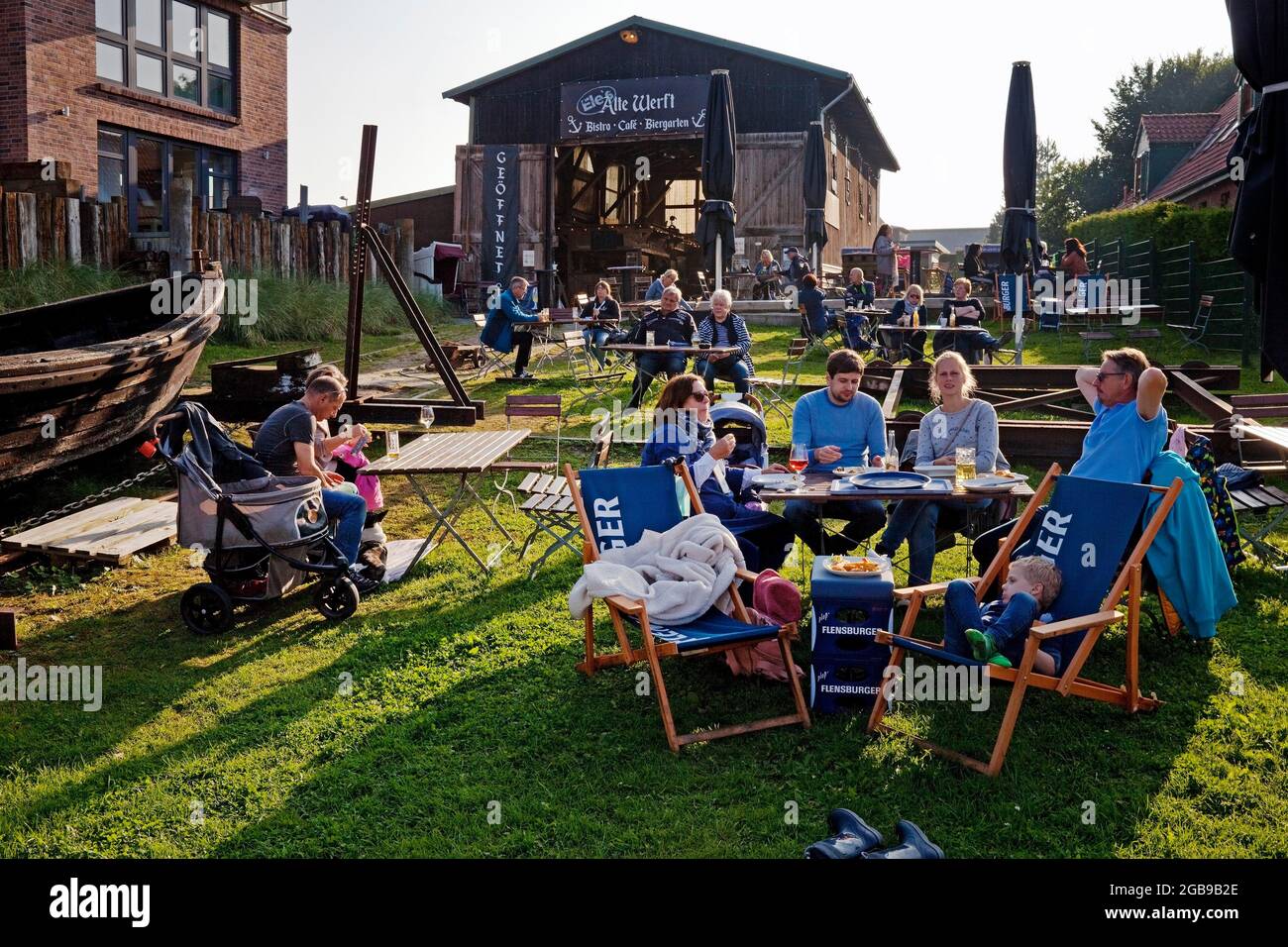 Gente en el jardín de la cerveza del antiguo astillero en el puerto histórico, Toenning, Frisia del Norte, Schleswig-Holstein, Alemania Foto de stock