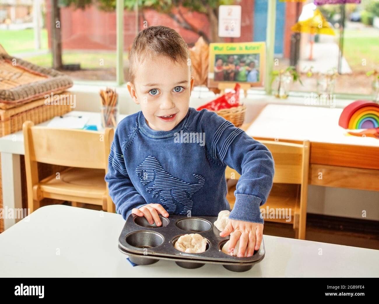 niño pequeño fingiendo cocinar pastelitos Foto de stock