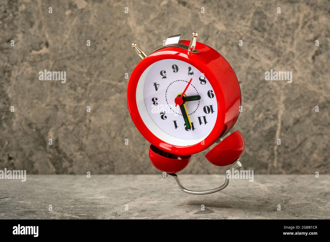 Reloj de alarma rojo cayendo sobre el fondo de piedra. Reloj de alarma rojo  que muestra las 9 de la mañana Fotografía de stock - Alamy