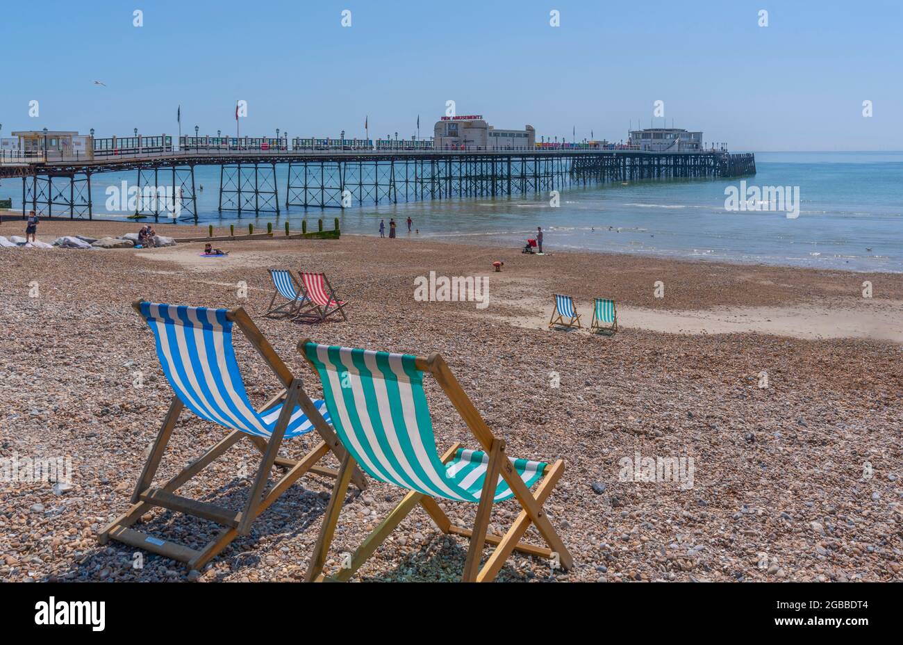 Vista de Worthing Pier y coloridas tumbonas en Worthing Beach, Worthing, West Sussex, Inglaterra, Reino Unido, Europa Foto de stock