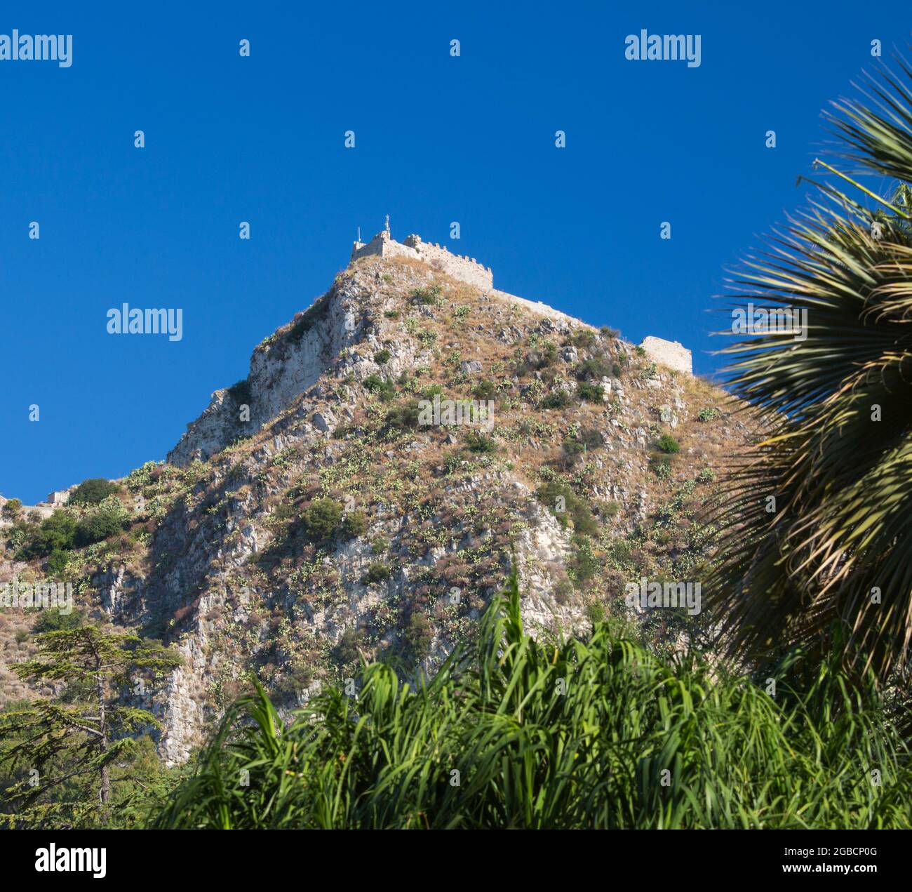 Taormina, Messina, Sicilia, Italia. Vista en ángulo bajo del castillo de Saracén en ruinas desde los jardines públicos de la Villa Comunale. Foto de stock