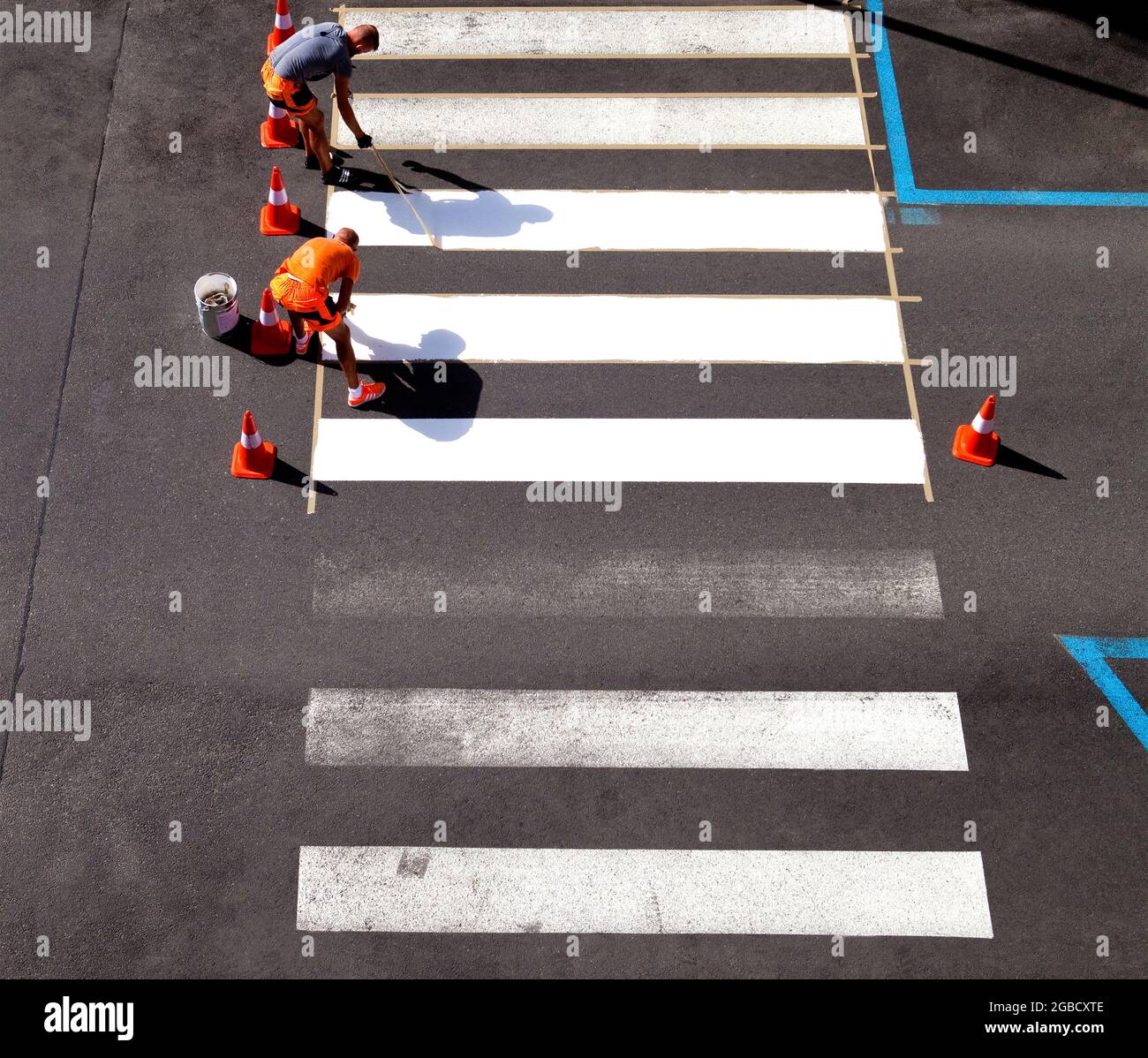 Los trabajadores pintan rayas cruzadas de color blanco. Foto de stock