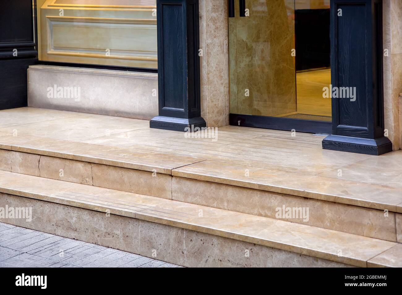 umbral de mármol claro con escalones en la entrada de la puerta de cristal  de un hotel caro con columnas de madera decorativa negra en la fachada de  cerca Fotografía de stock -