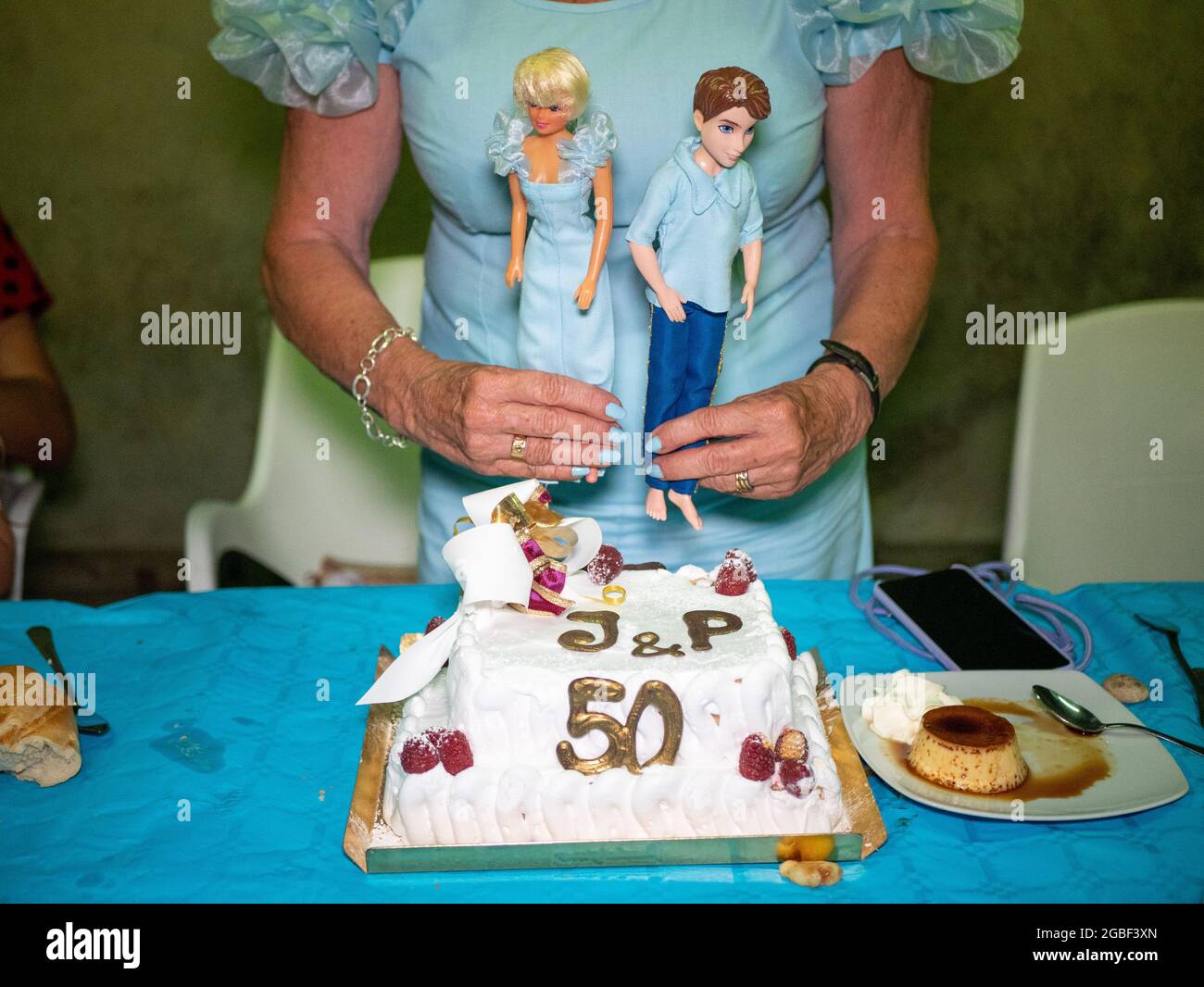 Mujer mayor sosteniendo muñecas de hombre y mujer por la torta para el  aniversario de la boda de 50th Fotografía de stock - Alamy