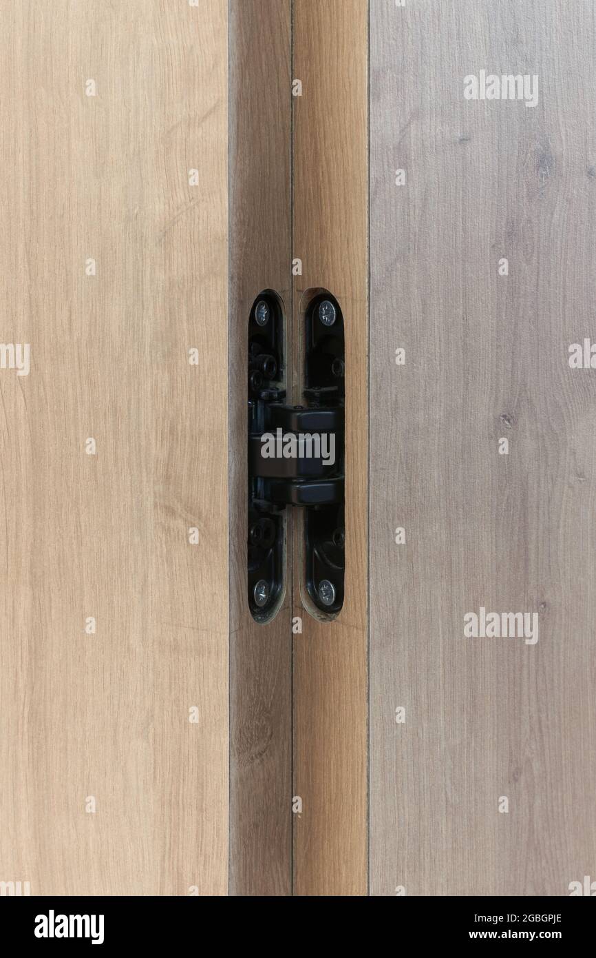 Primer plano de una bisagra negra oculta en una puerta de madera Fotografía  de stock - Alamy