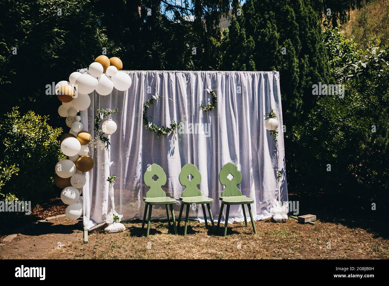 Vista de decoraciones de boda con globos y hojas con tres sillas verdes  delante de ella Fotografía de stock - Alamy