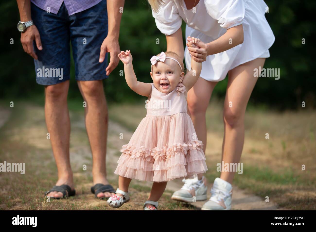 Feliz Nina De Un Ano De Edad Esta Siendo Llevada A Cabo Por Papa Y Mama Nino Pequeno Caminando Con Sus Padres Un Lindo Bebe Aprende A Caminar Con La Ayuda De