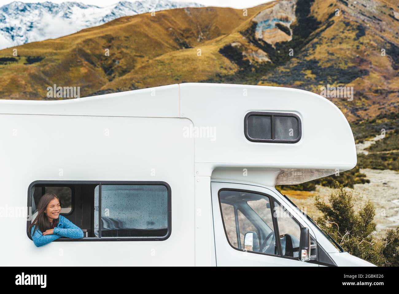 RV viaje por carretera mujer turística mirando por la ventana de su autocaravana en Nueva Zelanda viaje. Feliz joven asiática que viaja al aire libre en aventura Foto de stock