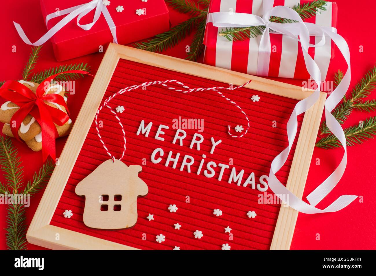 primer plano de fieltro rojo con el saludo de feliz navidad casa de madera  decorada y muchas cajas de regalo. Tarjeta de felicitación festiva para  vacaciones de invierno Fotografía de stock -