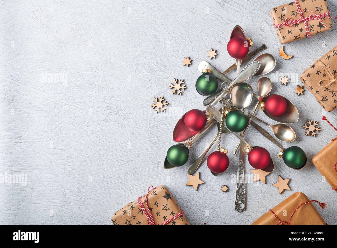 Árbol de Navidad hecho de cucharas antiguas o cubiertos con bolas de  Navidad rojas y verdes y cajas de regalos sobre fondo gris de piedra o  hormigón. Vista superior con Fotografía de