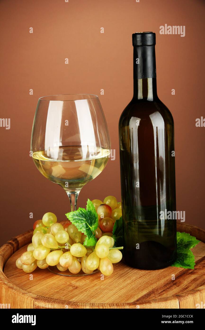 Composición de una botella de vino, una copa de vino blanco, de uva en  barril de madera, sobre fondo de color Fotografía de stock - Alamy