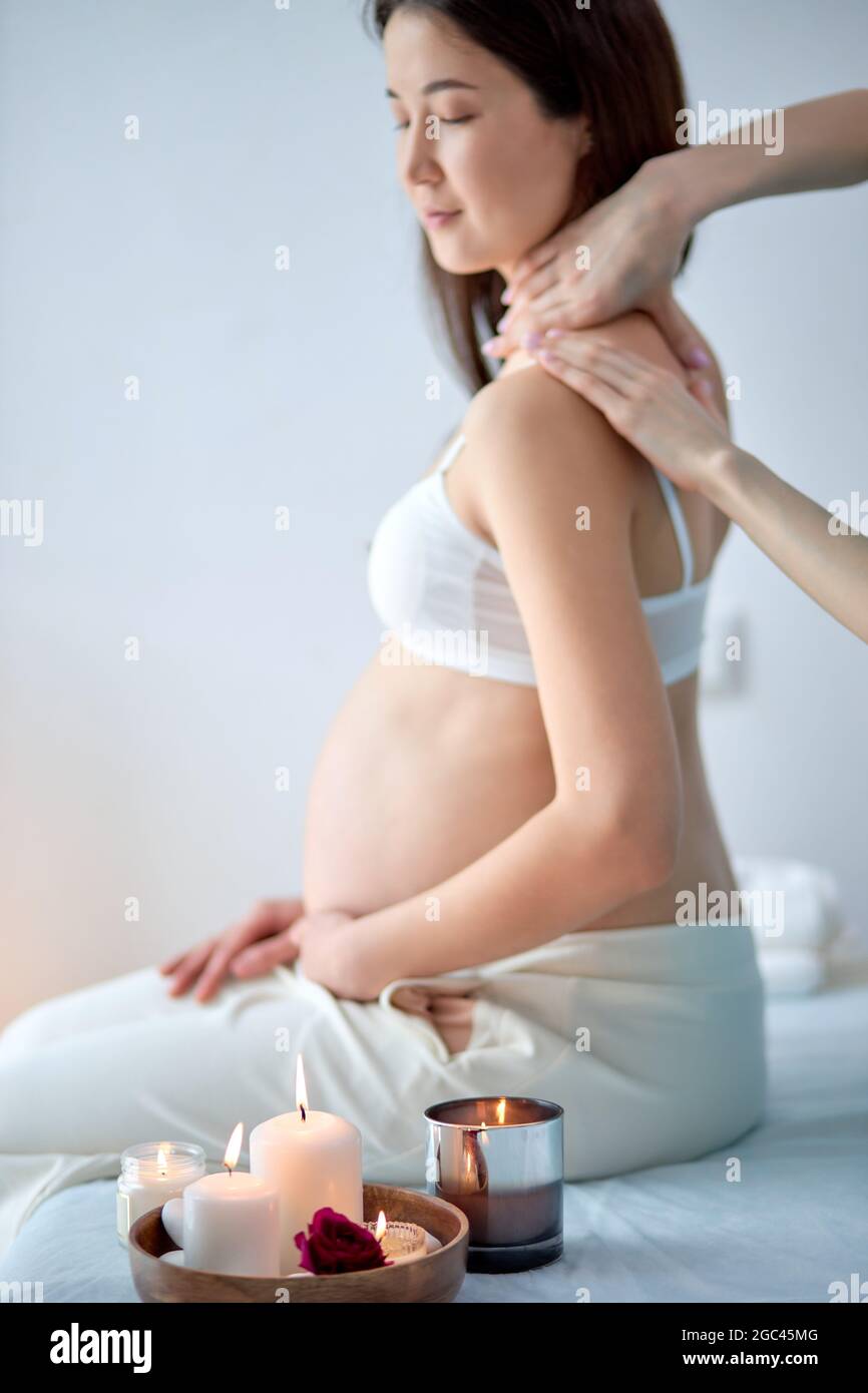 Mujer asiática sentada en la cama y con relajante masaje prenatal oriental en brazos, hombros y espalda. china en sujetador disfrutando del tiempo Fotografía de stock - Alamy