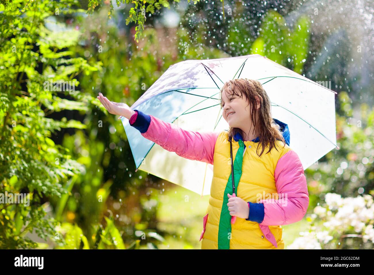 Niños jugando bajo la lluvia de otoño. Niño con paraguas. Niña corriendo en  un parque en la temporada de otoño. Diversión al aire libre para los niños  en cualquier clima. Chaqueta impermeable