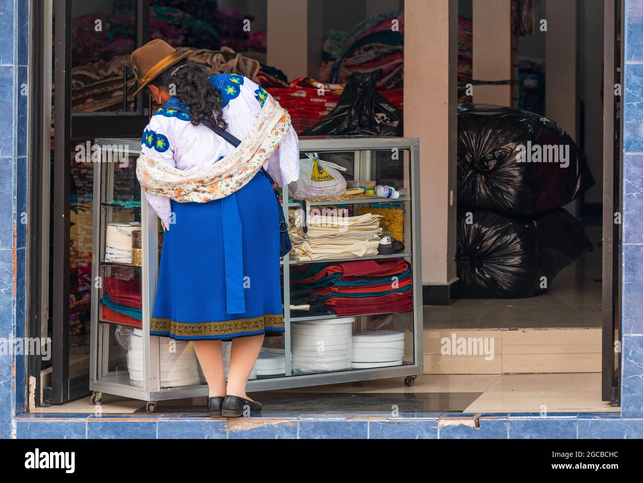 Mujer indígena ecuatoriana Otavalo en compras de ropa tradicional en la tienda de telas textiles, Otavalo, Ecuador. Foto de stock