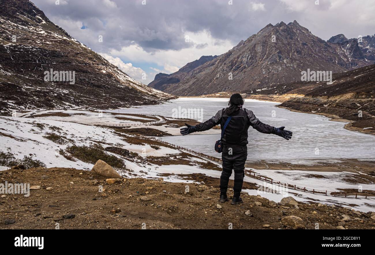 joven niña biker viajero en solitario en el lago congelado con fondo del valle de montaña en el día de la imagen se toma en el paso de sela tawang arunachal pradesh india. Foto de stock