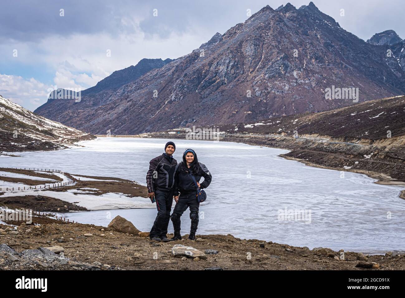joven pareja de biker en el lago congelado con fondo del valle de montaña en el día de la imagen se toma en el paso de sela tawang arunachal pradesh india. Foto de stock