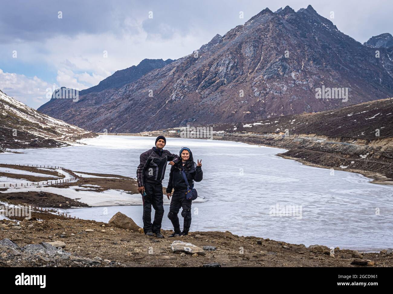 joven pareja de biker en el lago congelado con fondo del valle de montaña en el día de la imagen se toma en el paso de sela tawang arunachal pradesh india. Foto de stock