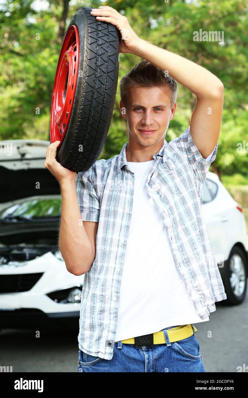 Hombre conductor sujetando el neumático en el hombro Fotografía de stock -  Alamy