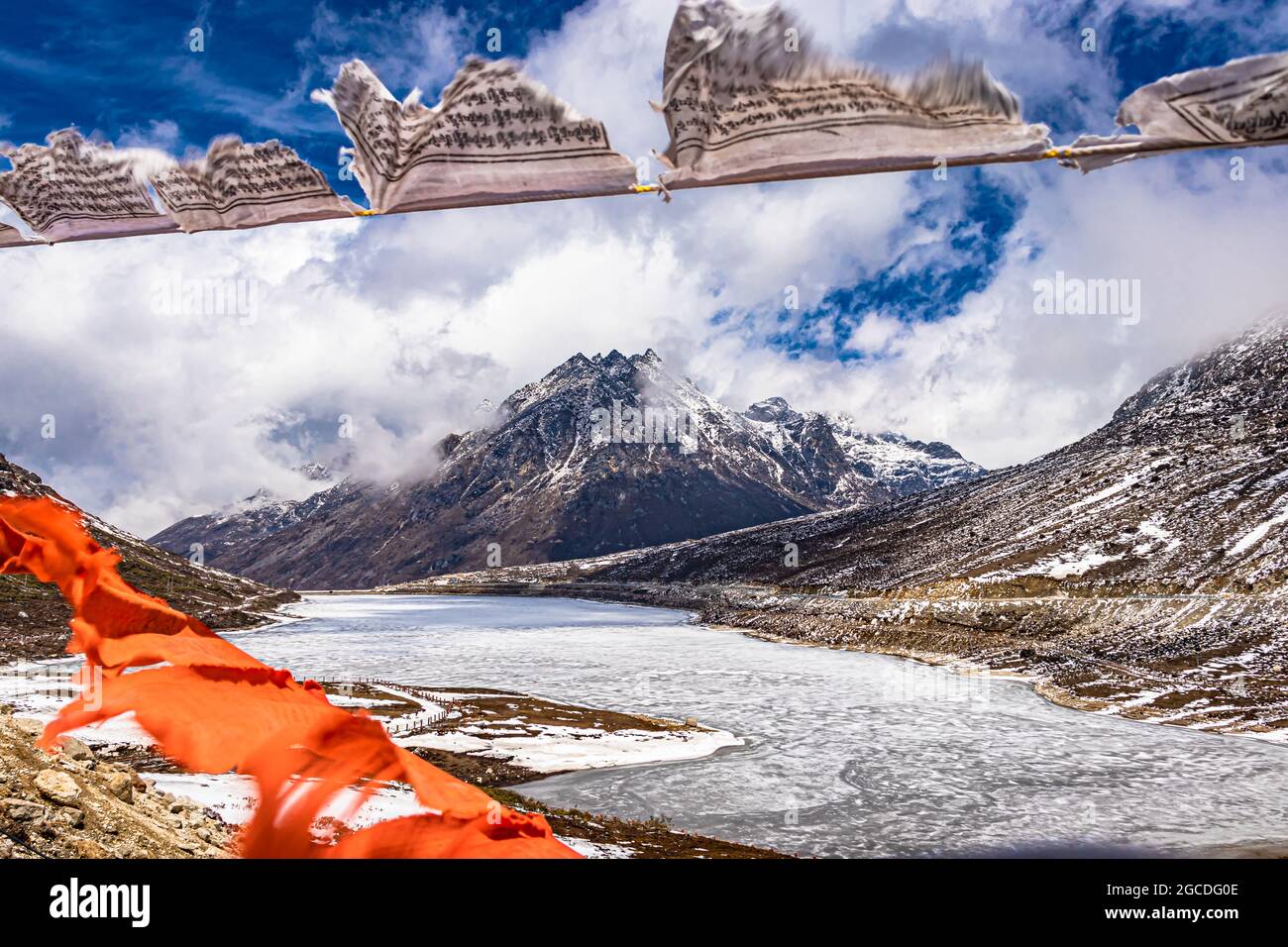 montaña nevada con cielo dramático a través del marco de las banderas del budismo borroso en el día de la imagen se toma en el paso de sela tawang arunachal pradesh india. Foto de stock