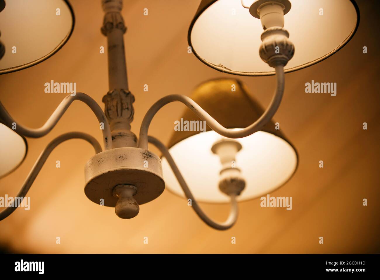 Lámparas brillantes con telas en tonos se iluminan en una elegante y hermosa araña por la noche, creando un ambiente acogedor. Un motel. Foto de stock
