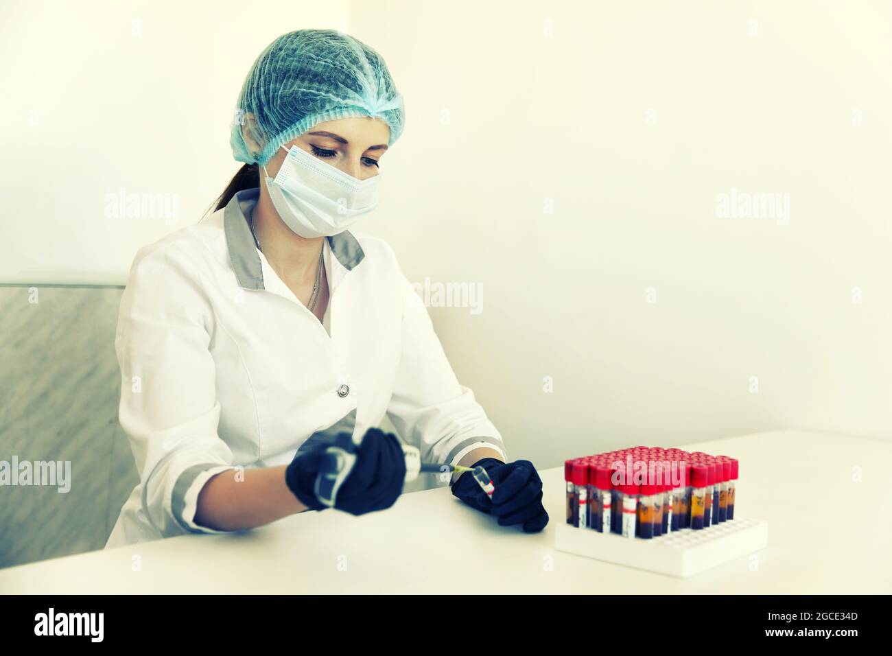 técnico de laboratorio con tubo de muestra de sangre y gradilla con otras  muestras. técnico de laboratorio que sostiene la muestra del tubo de sangre  para el estudio. tonificación sepia Fotografía de