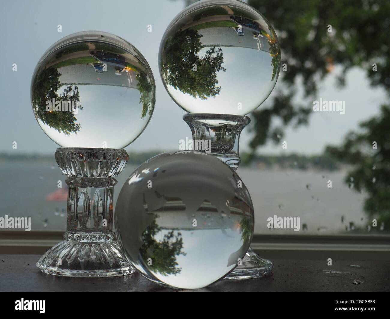 Tres esferas de vidrio que reflejan un lago y árboles Foto de stock