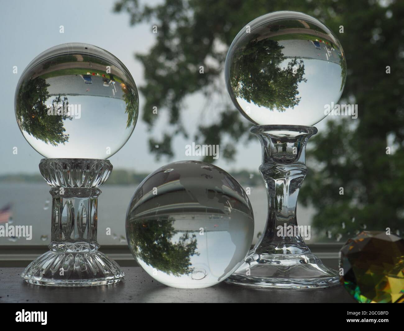Tres esferas de vidrio que reflejan un lago y árboles Foto de stock