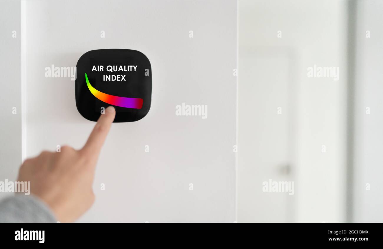 Índice de calidad del aire que se muestra en el dispositivo de tecnología domótica del hogar inteligente. La mujer toca la pantalla táctil para un filtro purificador de respiración de aire limpio. Foto de stock