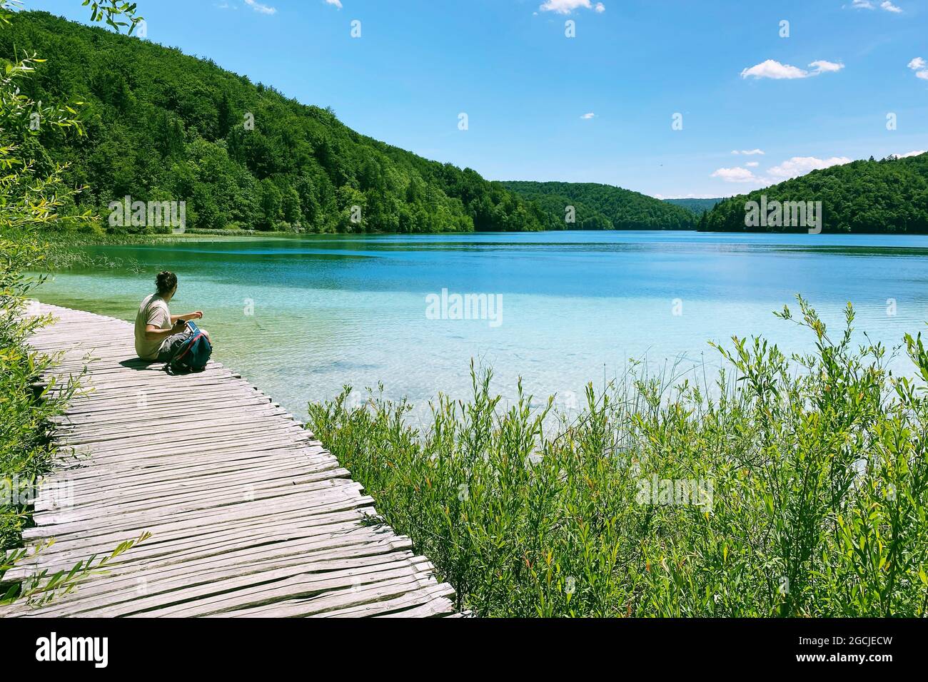 Turista relajante en la naturaleza. Paisajes de verano a lo largo del lago en viaje de viaje. Pasarela de madera vintage. Foto de stock